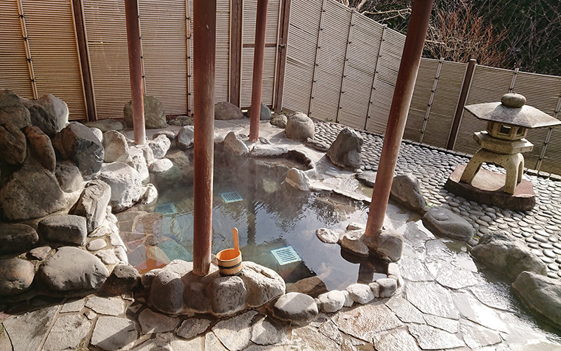 Japanese outdoor onsen surrounded by rocks and paving
