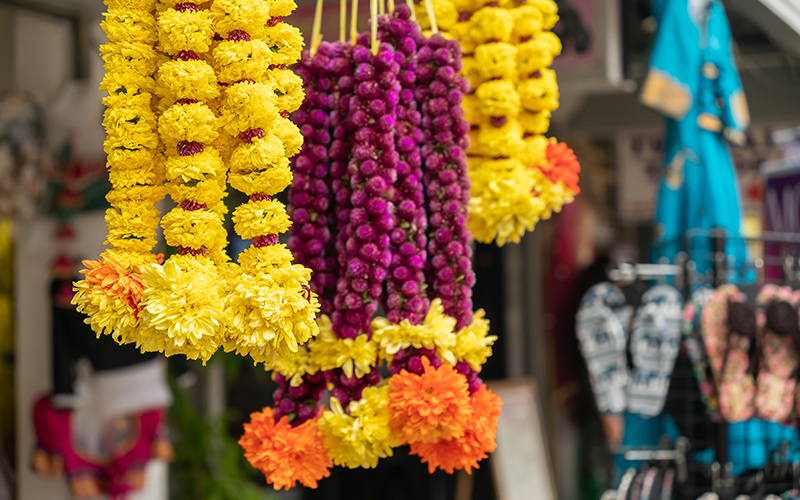 Pink and yellow floral garlands hanging at a market stall