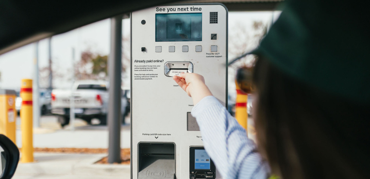 person putting in the parking ticket into the machine